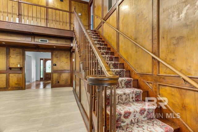 6505 Charing Wood Dr, Mobile, AL 36695 - stairway featuring wood walls, a high ceiling, wood finished floors, and a decorative wall