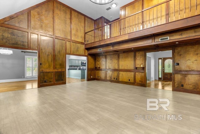 6505 Charing Wood Dr, Mobile, AL 36695 - unfurnished living room with a towering ceiling, a decorative wall, light wood finished floors, wooden walls, and arched walkways