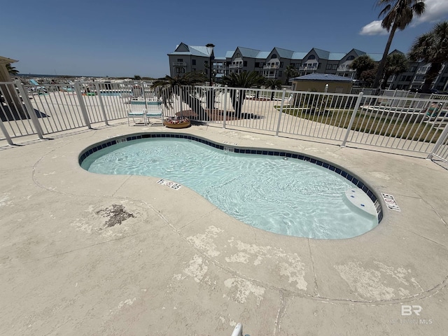 pool featuring a patio, fence, and a residential view