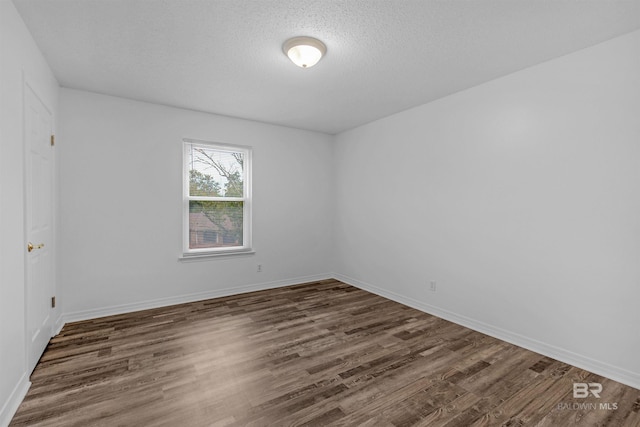 empty room featuring dark wood-type flooring and a textured ceiling