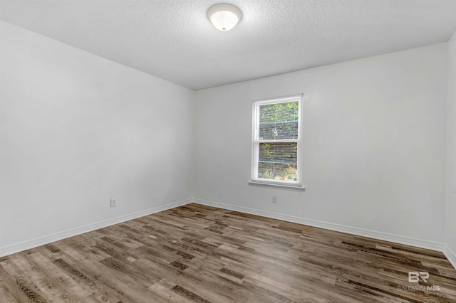 spare room featuring hardwood / wood-style floors and a textured ceiling