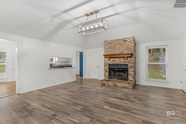 unfurnished living room featuring a fireplace, vaulted ceiling, and hardwood / wood-style flooring