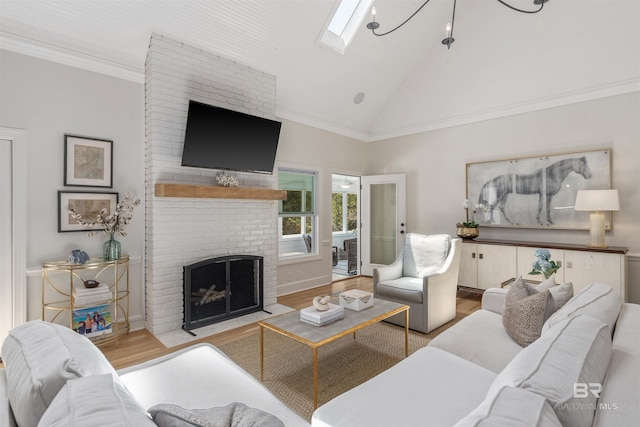 living area featuring high vaulted ceiling, wood finished floors, a skylight, a fireplace, and ornamental molding