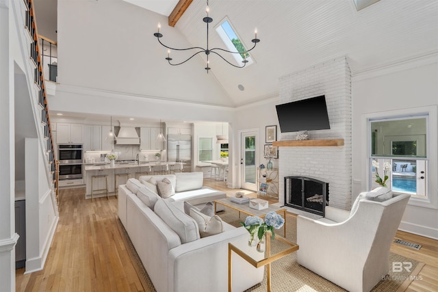 living area featuring high vaulted ceiling, light wood-style floors, a fireplace, a notable chandelier, and visible vents