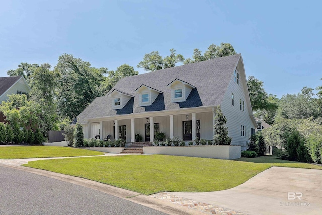new england style home with a porch, a shingled roof, and a front yard