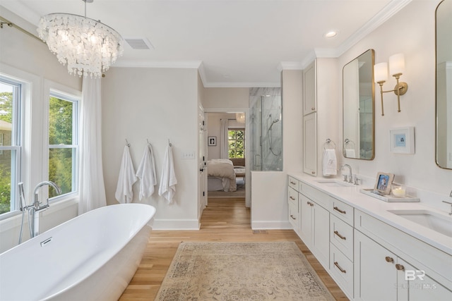 bathroom with wood finished floors, visible vents, crown molding, and a sink