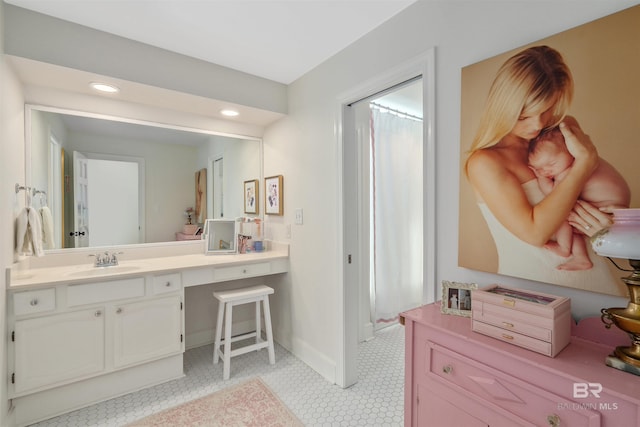 bathroom with baseboards, vanity, and recessed lighting