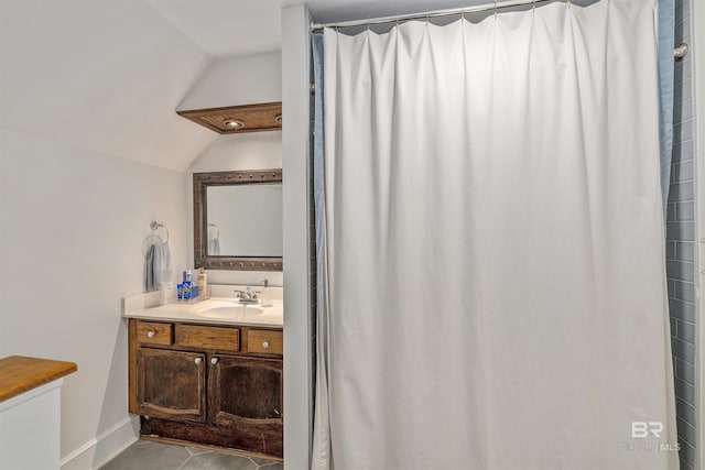 bathroom with baseboards, vaulted ceiling, tile patterned flooring, and vanity