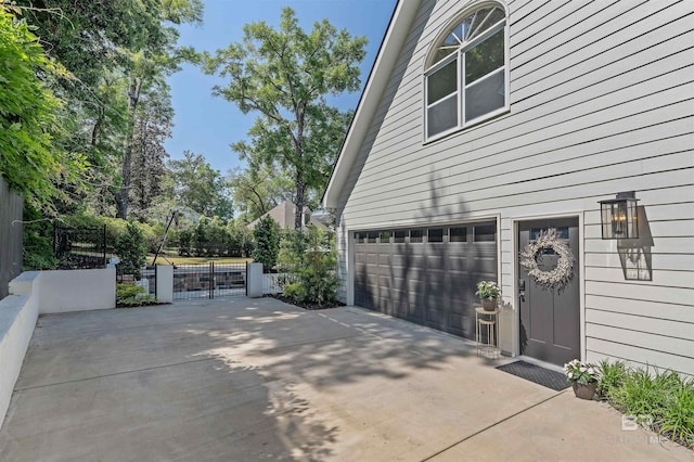 view of side of home featuring an attached garage, driveway, a gate, and fence