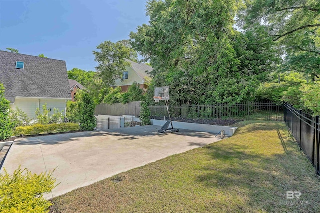 view of basketball court featuring a lawn and fence