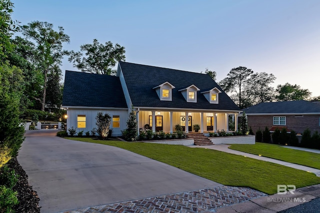 cape cod house with board and batten siding, driveway, a front lawn, and covered porch
