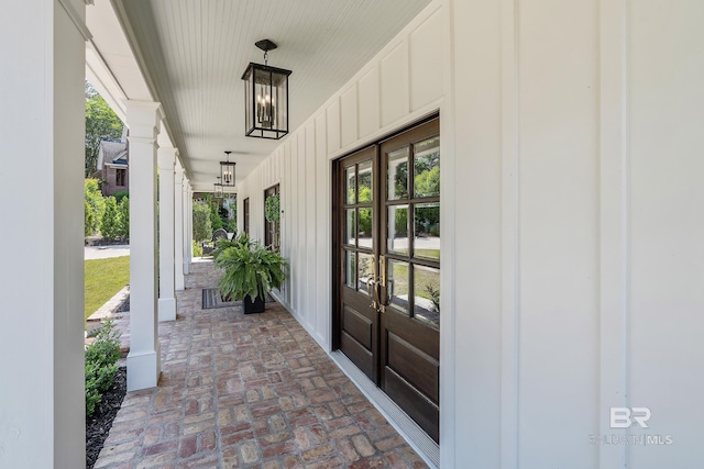 doorway to property with board and batten siding, covered porch, and french doors