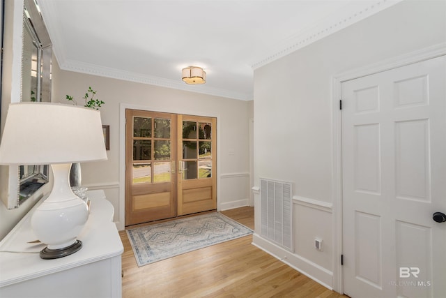 entryway featuring light wood-type flooring, visible vents, ornamental molding, and french doors
