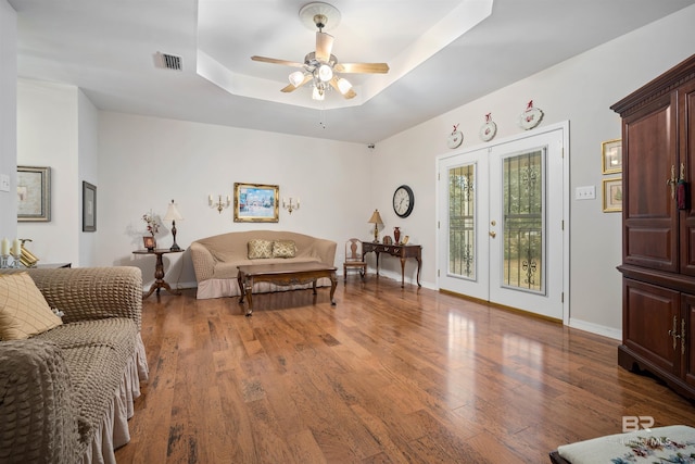 living room featuring hardwood / wood-style flooring, ceiling fan, french doors, and a tray ceiling