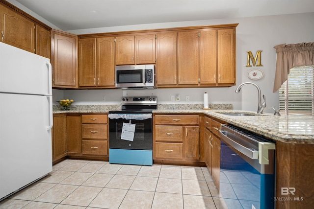 kitchen featuring light tile patterned floors, stainless steel appliances, light stone counters, and sink