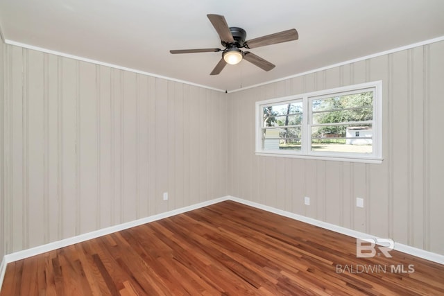 spare room featuring ceiling fan, baseboards, wood finished floors, and ornamental molding