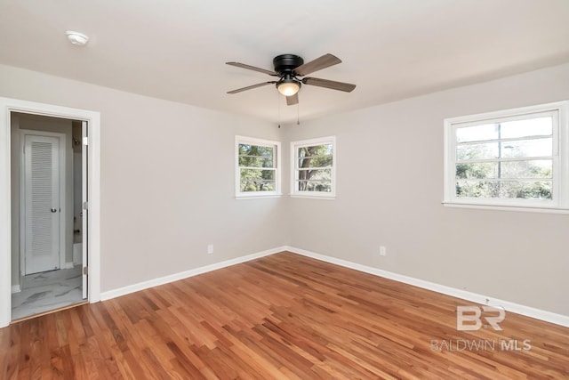 empty room featuring a ceiling fan, baseboards, and wood finished floors