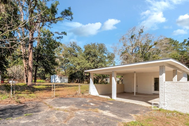 view of parking / parking lot with driveway and fence