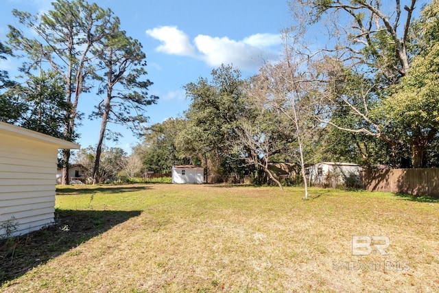 view of yard featuring an outdoor structure, fence, and a storage unit