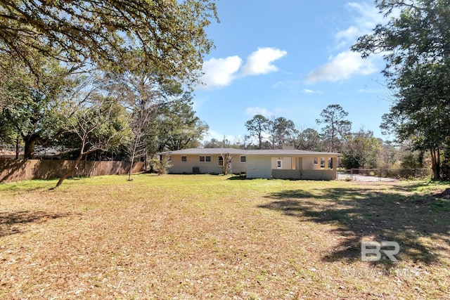 rear view of house featuring a lawn and fence