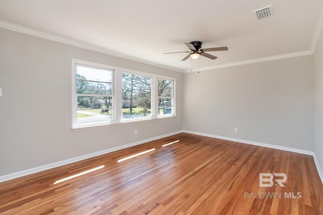 spare room with visible vents, baseboards, wood finished floors, and ornamental molding