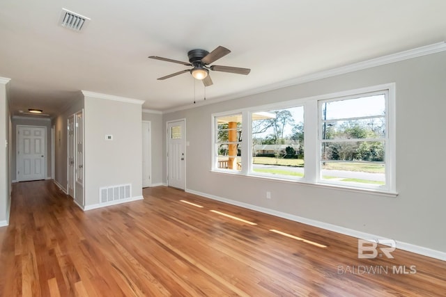 unfurnished living room featuring ornamental molding, visible vents, baseboards, and wood finished floors