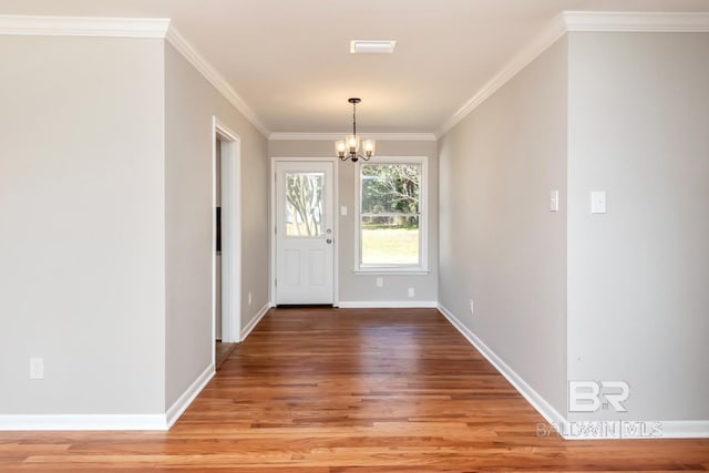 entryway featuring a chandelier, crown molding, wood finished floors, and baseboards