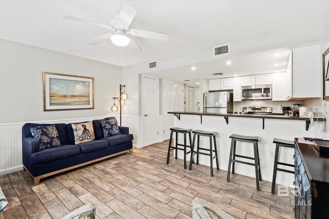 living room with ceiling fan and light hardwood / wood-style flooring