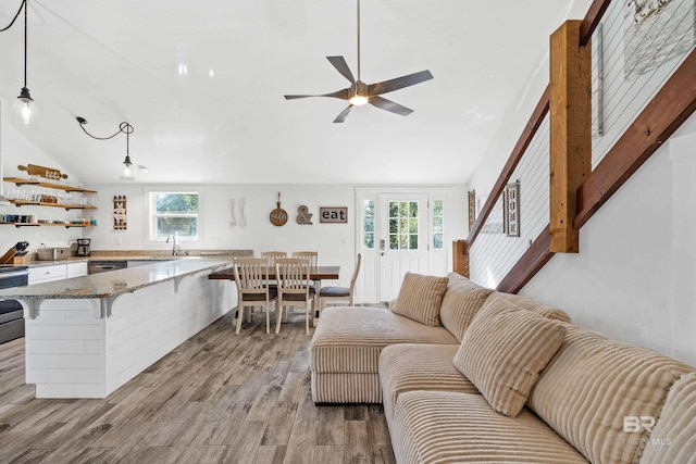 living room with sink, ceiling fan, light hardwood / wood-style floors, and vaulted ceiling