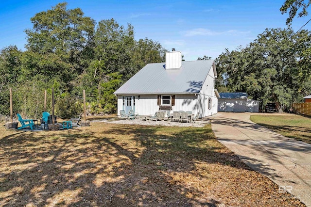 view of front facade with a front yard, a fire pit, and an outdoor structure