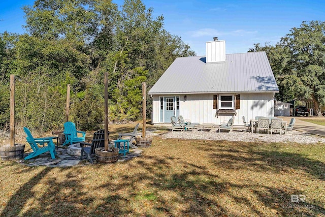 back of house with a lawn and an outdoor fire pit