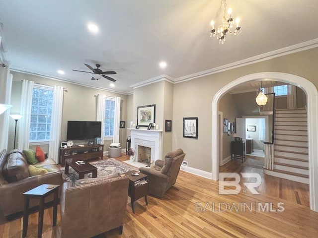 living room with a fireplace, crown molding, and light wood-type flooring