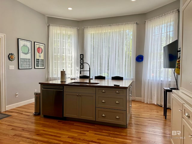 interior space with a healthy amount of sunlight, sink, light wood-type flooring, and stainless steel dishwasher