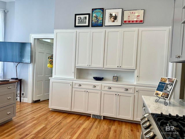 kitchen featuring white cabinetry, light wood-type flooring, and stainless steel range