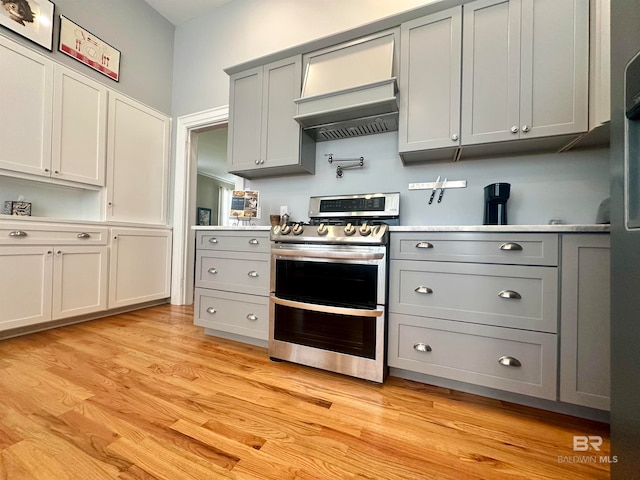 kitchen with gray cabinetry, custom exhaust hood, light hardwood / wood-style flooring, and electric stove