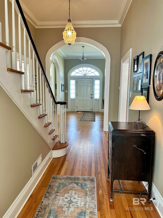 entryway with wood-type flooring and crown molding