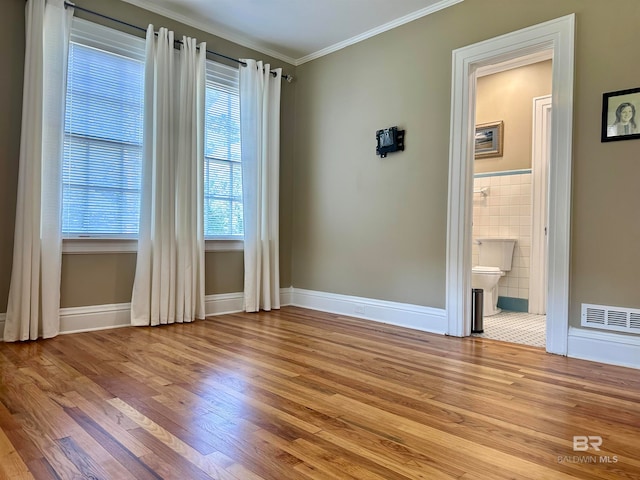 tiled empty room featuring crown molding and tile walls