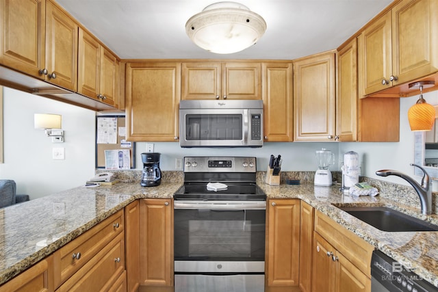 kitchen with stainless steel appliances, light stone counters, a peninsula, and a sink