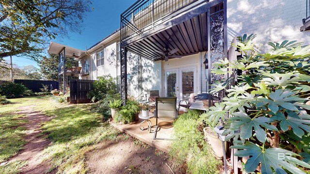 view of yard featuring ceiling fan, a balcony, and french doors