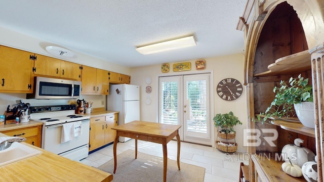 kitchen with white appliances, french doors, sink, a textured ceiling, and light tile patterned flooring