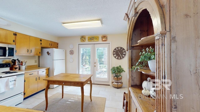 kitchen featuring white appliances, a textured ceiling, light tile patterned floors, and french doors