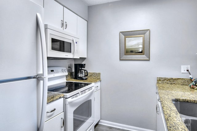 kitchen with baseboards, white cabinetry, white appliances, and light stone countertops