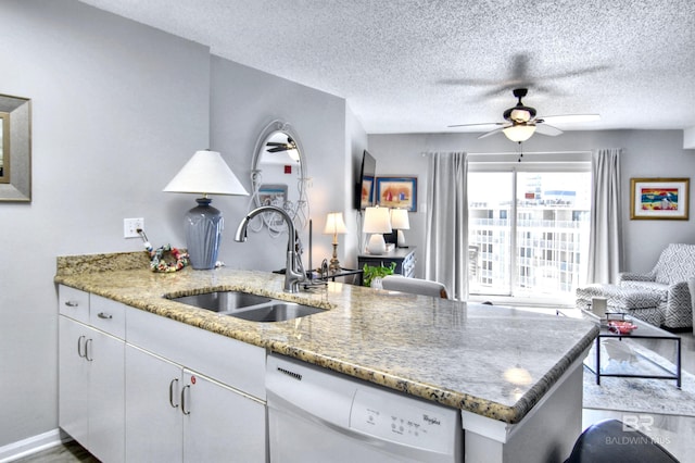 kitchen with light stone countertops, white cabinetry, a ceiling fan, a sink, and white dishwasher