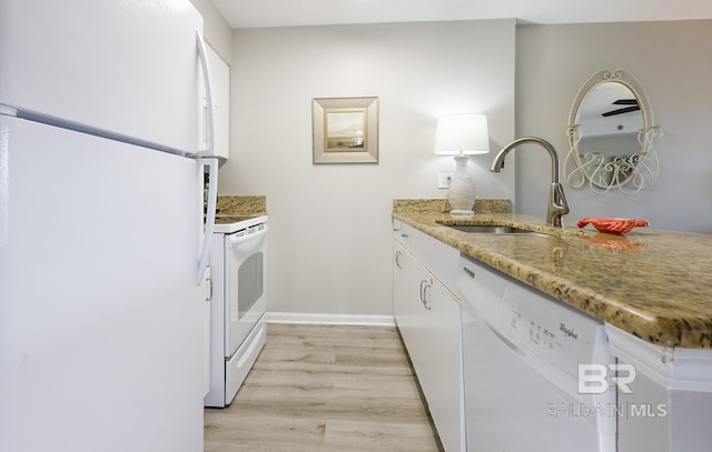 kitchen featuring white appliances, light stone countertops, light wood-type flooring, white cabinets, and a sink