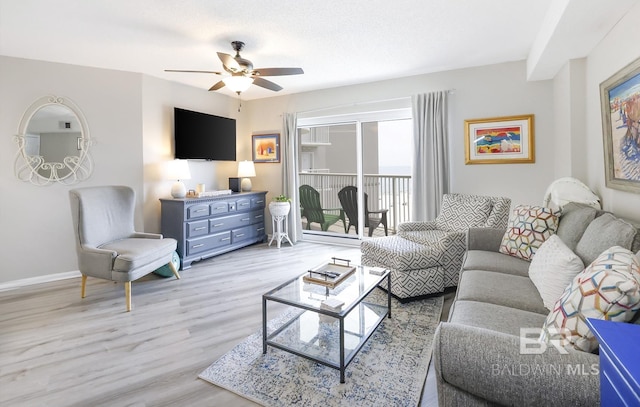 living area featuring baseboards, a ceiling fan, and wood finished floors