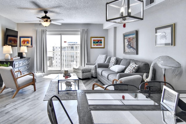 living room featuring a textured ceiling, wood finished floors, ceiling fan, and visible vents