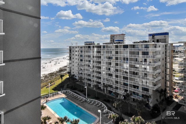 view of building exterior featuring a water view, a view of city, a community pool, and a beach view