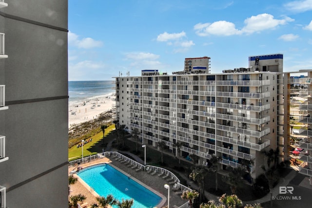 community pool featuring a water view, a city view, and a view of the beach