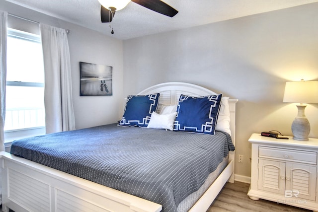 bedroom featuring a ceiling fan, wood finished floors, and multiple windows