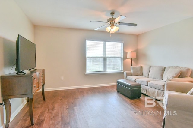 living room with ceiling fan, baseboards, and wood finished floors